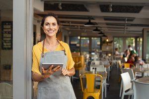 Proud young small business owner stands in front of her cafe.