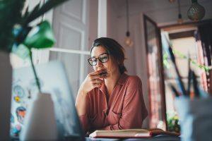 Woman working from home, sitting on the floor with a cat next to her.